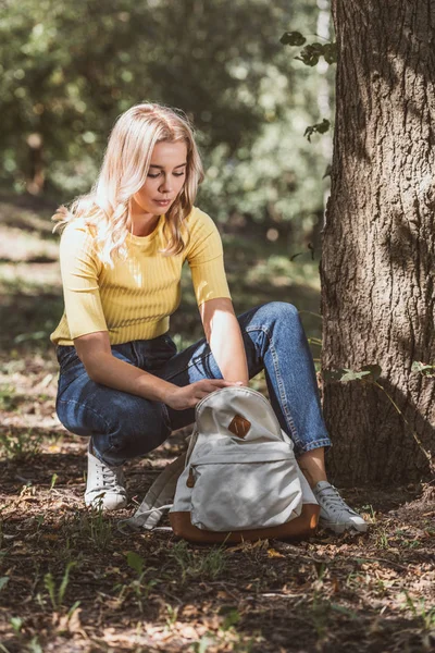 Junge Frau sucht im Wald nach etwas im Rucksack — Stockfoto