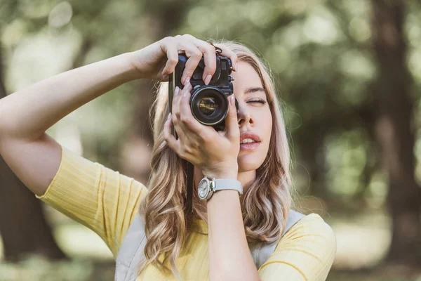 Portrait of young tourist with photo camera taking picture in park — Stock Photo