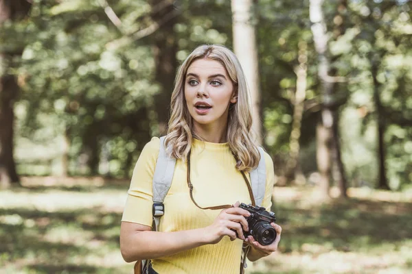 Retrato de jovem turista emocional com câmera de foto olhando para longe no parque — Fotografia de Stock