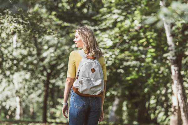 Вид ззаду молода блондинка з рюкзаком у лісі — стокове фото