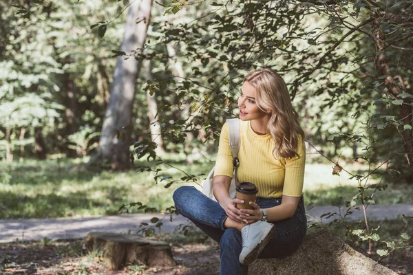 Beautiful young woman with coffee to go resting in park — Stock Photo
