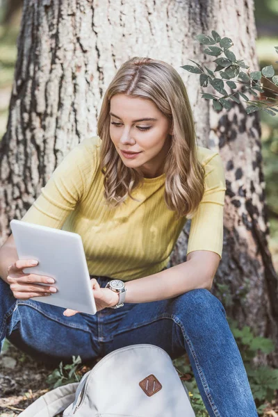 Retrato de mulher jovem usando tablet digital enquanto descansa no parque — Fotografia de Stock