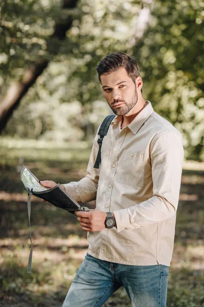 Portrait of young tourist with map in hands looking at camera in park — Stock Photo