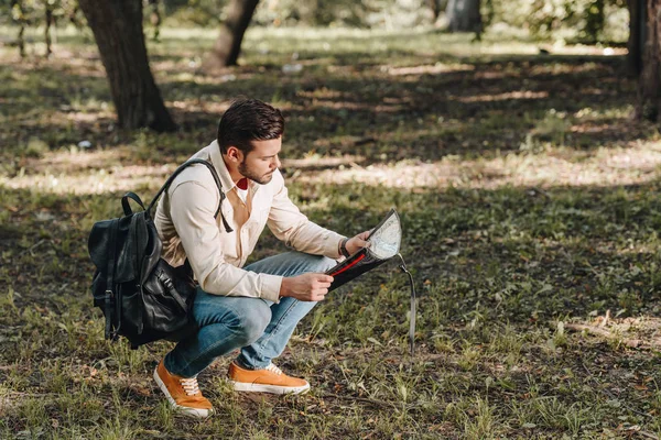 Vista laterale del turista con mappa e zaino nel parco — Foto stock