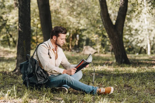 Side view of traveler with map and backpack in park — Stock Photo
