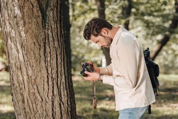 Side view of young traveler with photo camera in park — Stock Photo