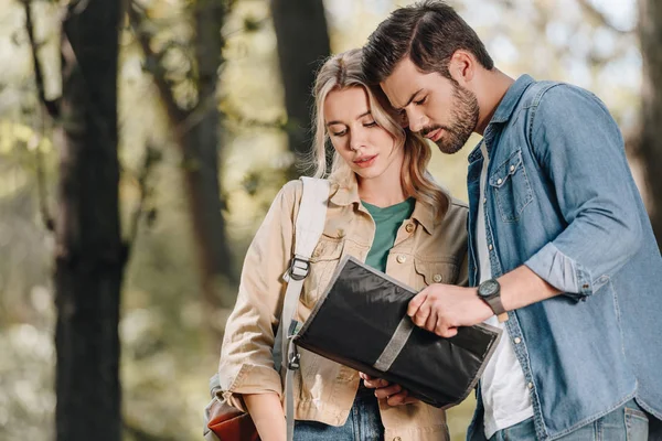 Portrait of couple of tourists looking for destination on map in park — Stock Photo