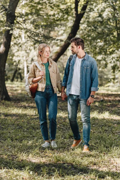 Young stylish couple holding hands during romantic date in autumn park — Stock Photo