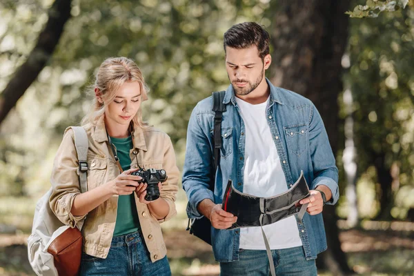 Портрет пары туристов с фотокамерой и картой в парке — стоковое фото