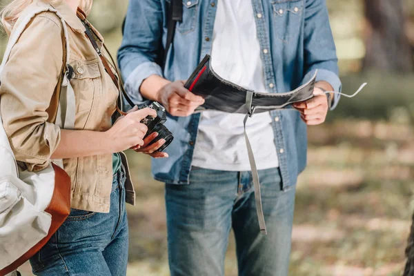 Partial view of couple of tourists with photo camera and map in park — Stock Photo
