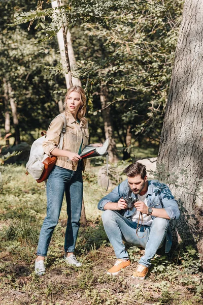 Pareja de jóvenes viajeros con mapa y cámara fotográfica en el parque - foto de stock
