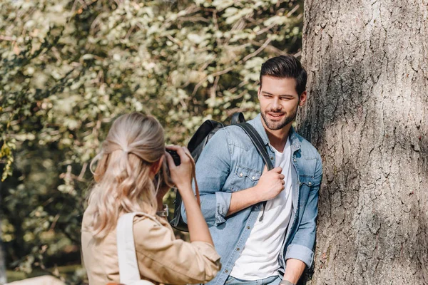 Femme prenant des photos de copain élégant dans le parc d'automne — Photo de stock