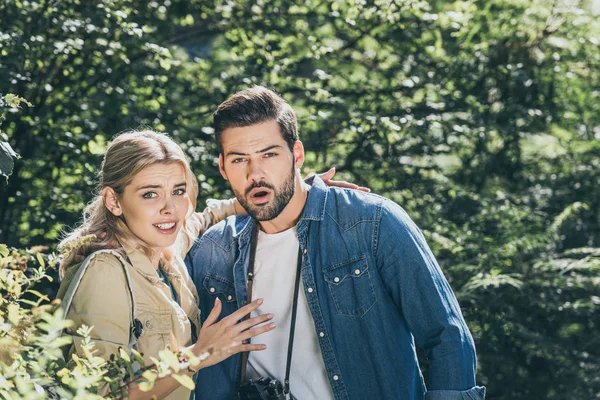 Portrait of shocked couple of tourists with photo camera in park — Stock Photo