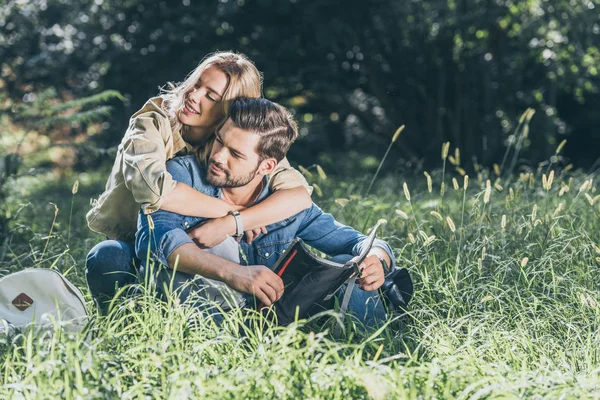 Портрет улыбающейся женщины, обнимающей парня с картой в руках в парке — стоковое фото