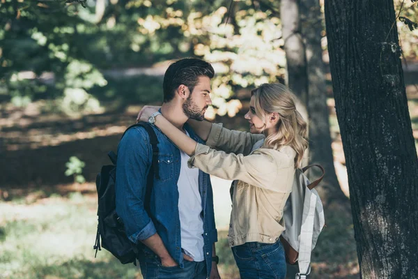 Young couple with backpacks looking at each other in park — Stock Photo