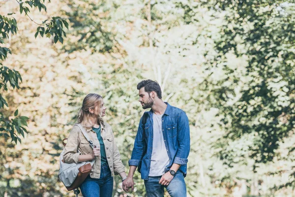 Retrato de pareja joven y elegante tomados de la mano en el parque de otoño - foto de stock