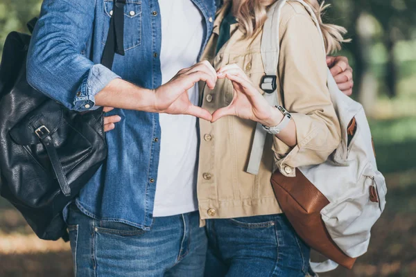 Partial view of romantic couple showing heart sign made with hands in autumn park — Stock Photo