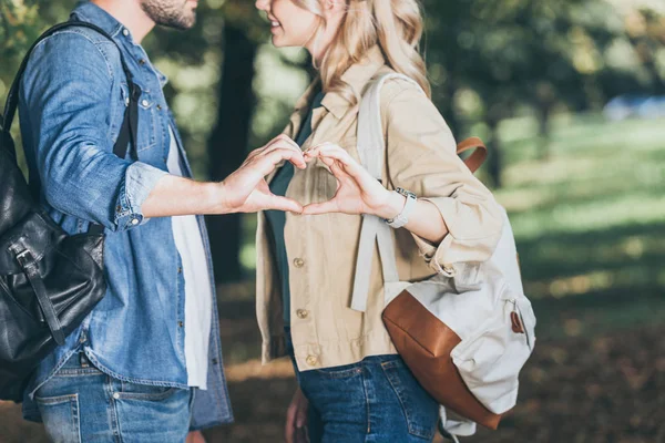 Vista parziale di coppia romantica mostrando il segno del cuore fatto con le mani nel parco autunnale — Foto stock