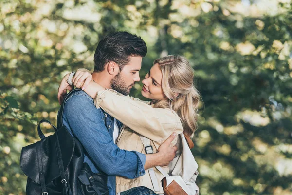 Vista lateral de pareja romántica joven abrazándose en el parque de otoño - foto de stock