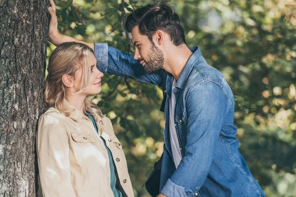 Vista lateral de jovem casal romântico olhando uns para os outros no parque de outono — Fotografia de Stock
