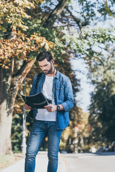 Young focused traveler with map standing on street — Stock Photo