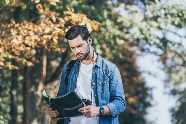 Portrait de jeune voyageur concentré avec carte debout dans le parc d'automne — Photo de stock