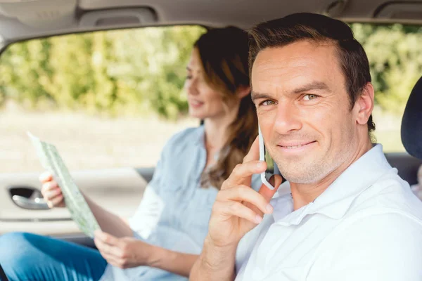 Close-up shot of happy adult couple travelling by car while man talking by phone — Stock Photo