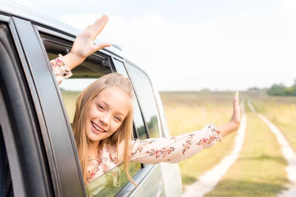 Celebrando a un niño pequeño mirando por la ventana del coche mientras monta por el campo - foto de stock