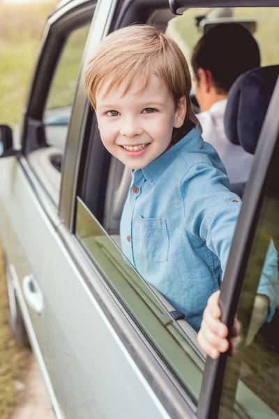 Счастливый маленький ребенок едет на машине со своим отцом на природе и смотрит в камеру — стоковое фото