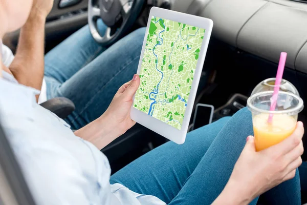 Plan recadré de la femme avec tasse en plastique de jus d'orange à l'aide d'une tablette avec carte à l'écran dans la voiture — Photo de stock