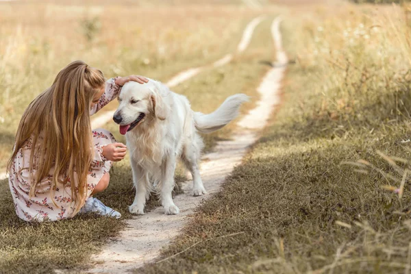 Beautiful little child with adorable golden retriever dog in field — Stock Photo