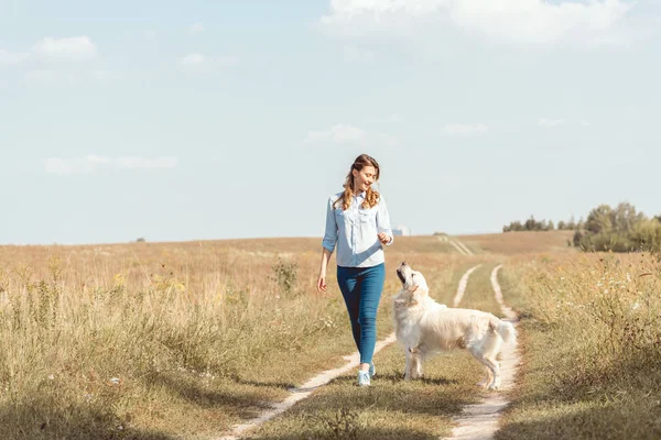 Hermosa mujer adulta caminando por el campo con perro retriever - foto de stock