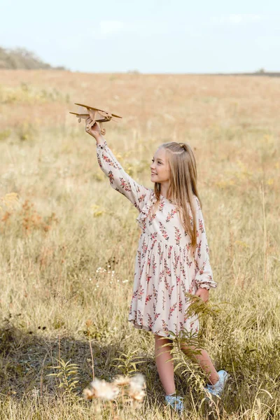 Linda criança brincando com avião de brinquedo no campo — Fotografia de Stock