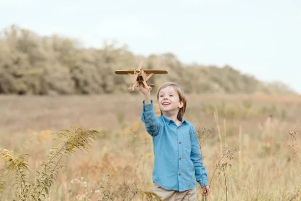 Happy little kid in field playing with toy airplane in field — Stock Photo