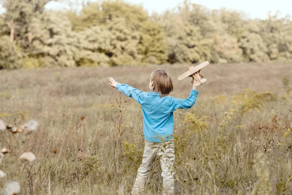 Vue arrière du petit enfant sur le terrain jouant avec l'avion jouet sur le terrain — Photo de stock