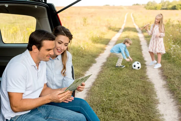 Счастливая молодая семья проводит время в поле, путешествуя на машине — стоковое фото