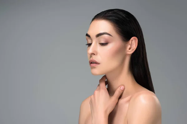 Jeune femme brune nue touchant le cou avec la main et regardant loin isolé sur gris — Photo de stock