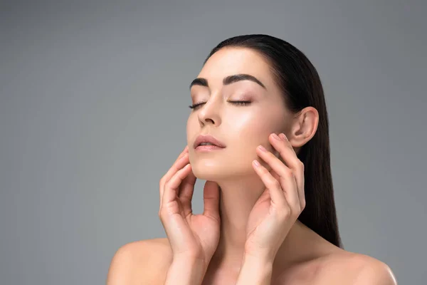 Portrait of beautiful sensual naked brunette woman touching face with hands isolated on grey — Stock Photo