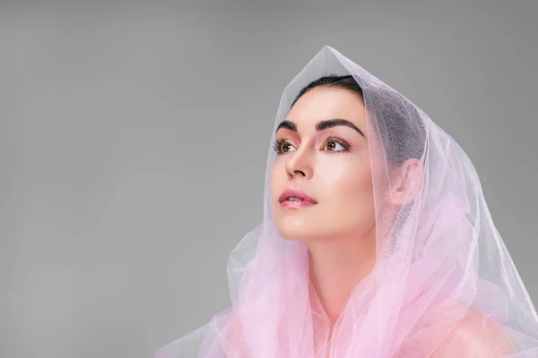 Beautiful young woman with pink veil looking up isolated on grey — Stock Photo