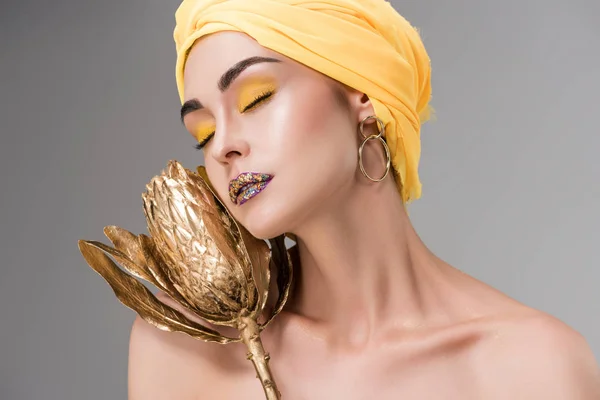 Sensual naked girl in yellow turban holding golden protea flower isolated on grey — Stock Photo