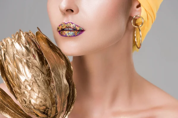 Обрезанный снимок чувственной женщины с блестящими губами, держащих золотой цветок Протея, изолированный на сером — стоковое фото
