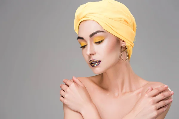 Hermosa chica desnuda sensual en envoltura de cabeza amarilla mirando hacia abajo aislado en gris — Stock Photo