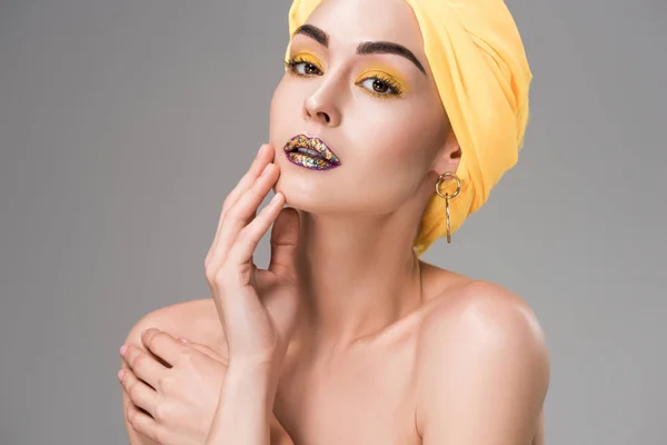 Menina nua bonita com maquiagem elegante vestindo turbante amarelo e olhando para a câmera isolada no cinza — Fotografia de Stock