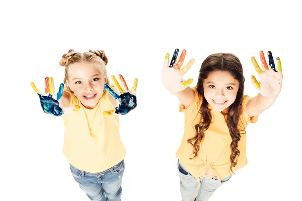 Visão de alto ângulo de crianças adoráveis mostrando mãos pintadas coloridas e sorrindo para a câmera isolada no branco — Fotografia de Stock