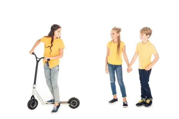 Happy child riding scooter and looking at friends holding hands isolated on white — Stock Photo