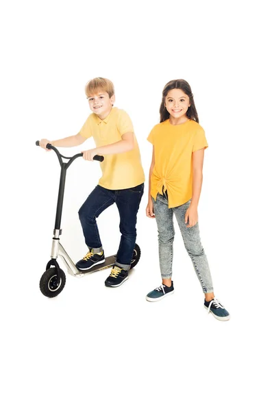 Vue grand angle des enfants heureux debout avec scooter et souriant à la caméra isolée sur blanc — Photo de stock