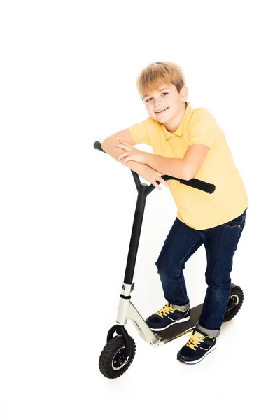 Lindo niño feliz apoyado en scooter y sonriendo a la cámara aislado en blanco - foto de stock