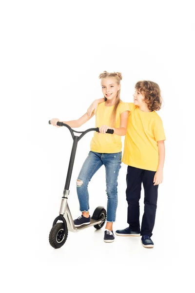 Vue pleine longueur d'adorables enfants heureux debout avec scooter isolé sur blanc — Photo de stock