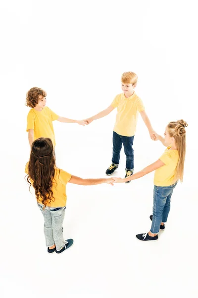 Vista de ángulo alto de lindos niños felices de pie juntos y tomados de las manos aislados en blanco - foto de stock
