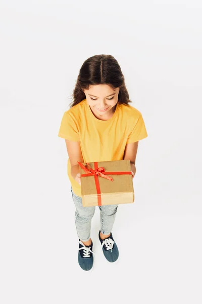 High angle view of adorable smiling kid holding gift box isolated on white — Stock Photo